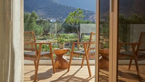 A balcony with wooden furniture, a view of a mountainous landscape, and a glass door. - Villa Elounda Lion, 2 Pools, Hammam & Close to Sea (Agios Nikolaos)