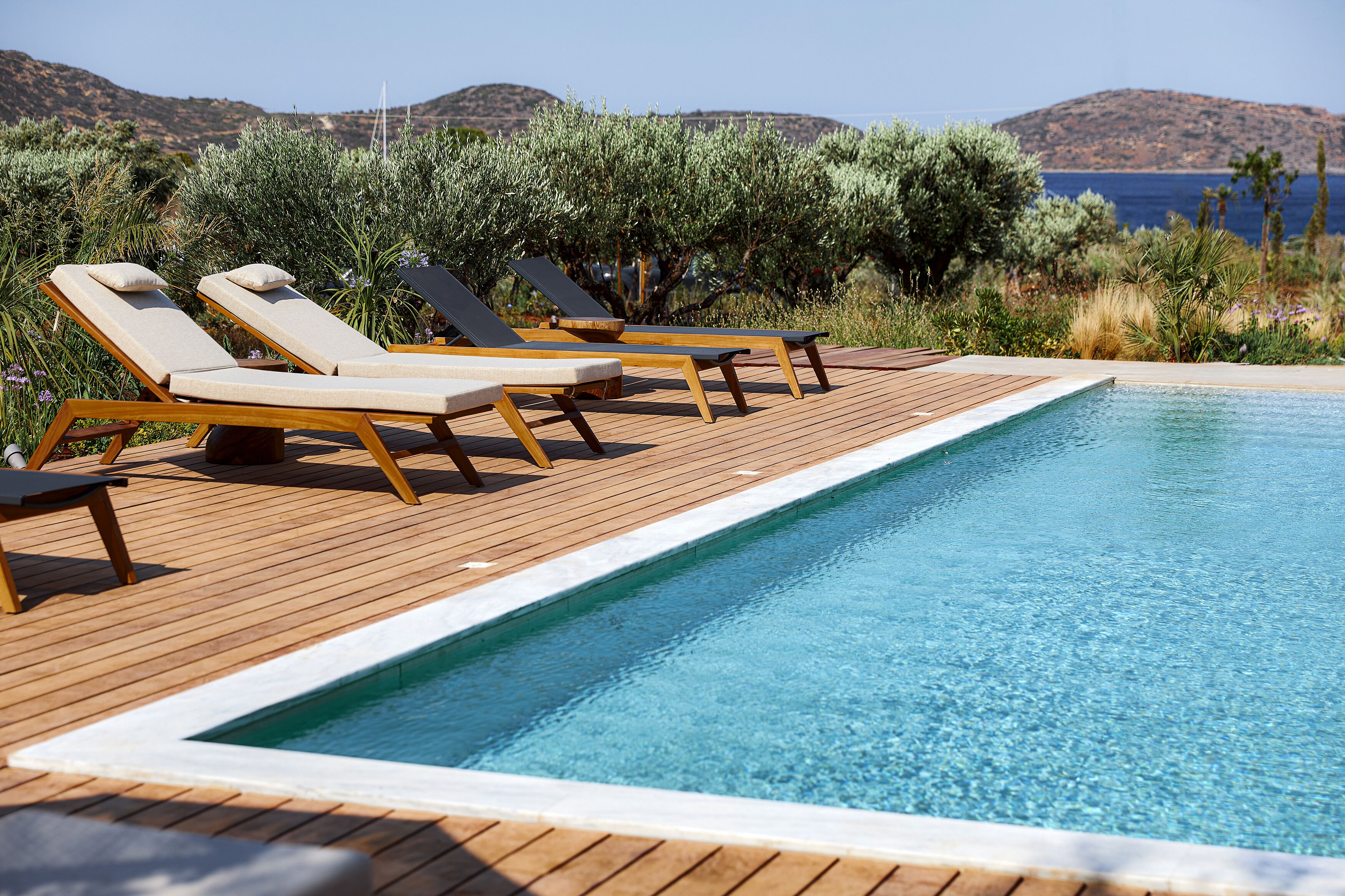Un espace aménagé au bord de la piscine, avec une terrasse en bois et des chaises longues.
