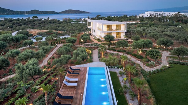 A modern villa with a swimming pool, surrounded by landscaped gardens and overlooking a coastal area. - Villa Elounda Lion, 2 Pools, Hammam & Close to Sea (Agios Nikolaos)