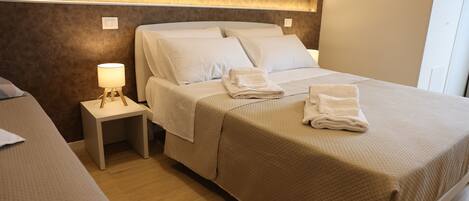 A hotel room with a large bed, a bedside table with a lamp, and a wall-mounted light.