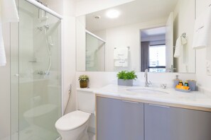 A modern bathroom with a glass-enclosed shower, a toilet, a sink with a mirror above it, and a cabinet below. - Piscina na cobertura e Academia  (Sao Paulo)