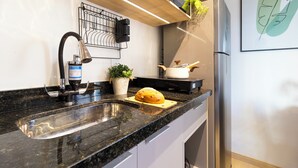 A kitchen with a granite countertop, stainless steel sink, and a potted plant.