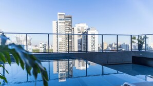 A rooftop pool with a cityscape view, surrounded by glass railings.