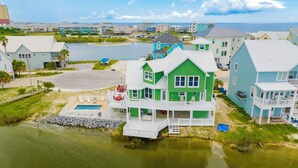 Une maison à plusieurs étages avec une piscine, un quai et une vue sur l’océan.