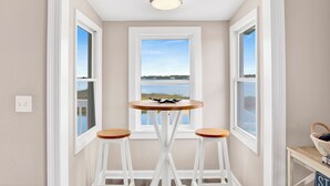 Une pièce avec vue sur un lac, une table ronde avec deux tabourets et un luminaire au plafond.