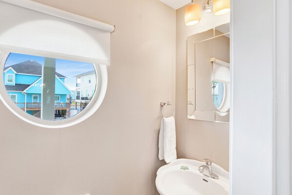 Une salle de bain avec une fenêtre ronde, un lavabo et un miroir.