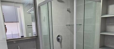 A modern bathroom with a glass-enclosed shower, a sink with a mirror, and a toilet.