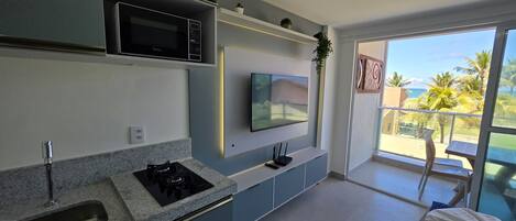 Une cuisine moderne équipée d’un four à micro-ondes encastré, d’un téléviseur à écran plat et d’une cuisinière à gaz.