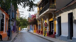 A street with colorful buildings, including a hotel with a balcony and flower boxes.