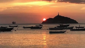 A sunset over a body of water with several boats and a distant island.