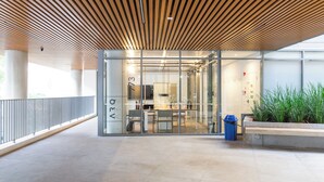 A modern building with a wooden slatted ceiling, glass walls, and a seating area with tables and chairs. - ARQ Vila Mariana (Sao Paulo)