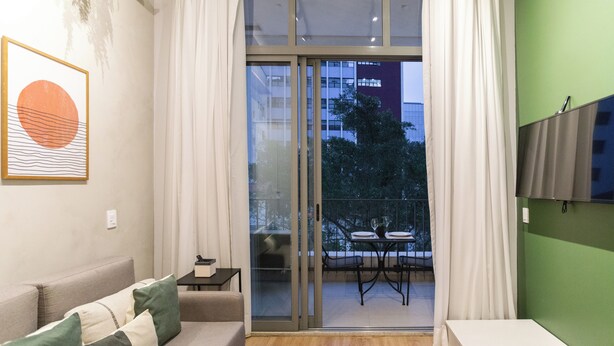A modern living room with a sofa, a small table, and a TV mounted on the wall. - ARQ Vila Mariana (Sao Paulo)