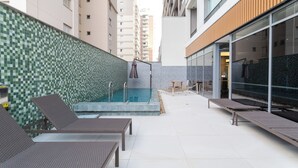 A rooftop pool area with lounge chairs, a small pool, and a glass wall. - ARQ Vila Mariana (Sao Paulo)
