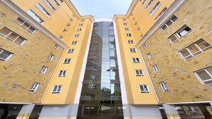 En symmetrisk byggnad med en central glasfasad och flera fönster på varje sida.