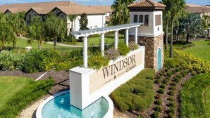 Zona residencial con piscina, un letrero que dice "Windsor" y casas de estilo arquitectónico mediterráneo.