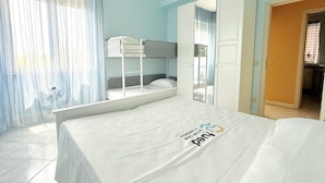 Ett hotellrum med en våningssäng, en stor spegel och en säng med en tydlig logotyp.