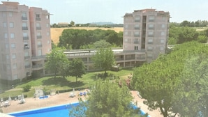 En bostadsbyggnad med flera balkonger, en swimmingpool och ett vackert anlagt trädgårdsområde.