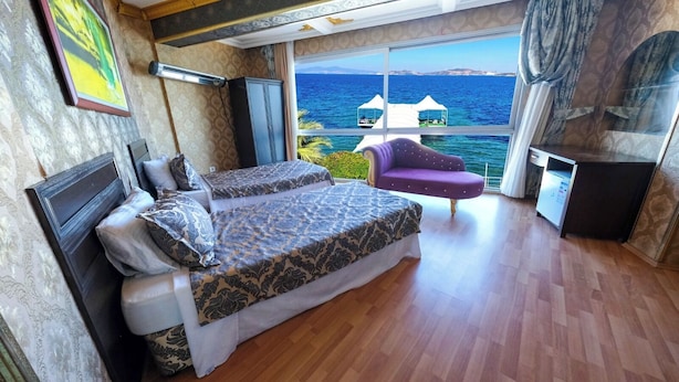 Une chambre avec deux lits, un petit coin salon et vue sur la mer.