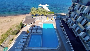 Un espace piscine avec des chaises longues et un petit bâtiment doté d’un toit blanc.