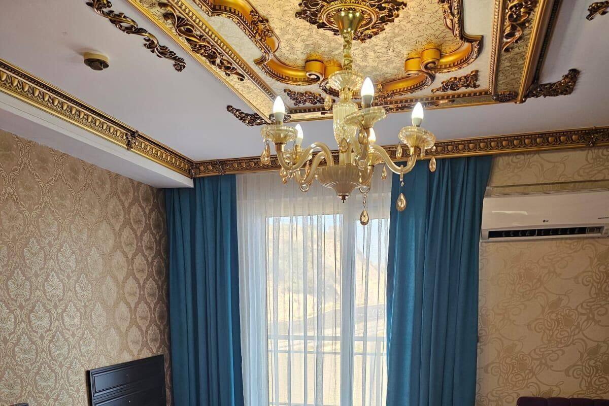 A hotel room with a large bed, a chest of drawers, a vanity, and a chandelier.