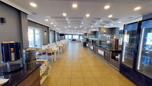 Un restaurant long et étroit, avec une allée centrale et des tables et des chaises de chaque côté.