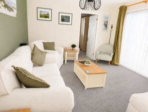 A living room with a sofa, a coffee table, and a chair. There is a door leading to another room. - Welcome to your cosy coastal English home from home. Free Parking. Highly rated. (Southampton)