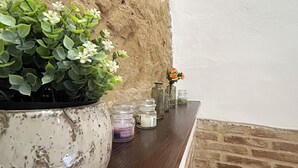 A rustic interior with a large potted plant, small jars, and a wooden shelf against a textured wall. - The Bishop's Residence (Stimigliano)