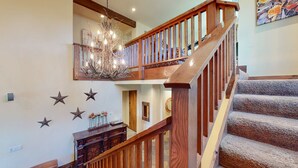A wooden staircase with a railing, a chandelier, and a wall decorated with stars and a mirror. - Snowcreek Vi The Lodges #1197 3 Bedroom Condo (Mammoth Lakes)