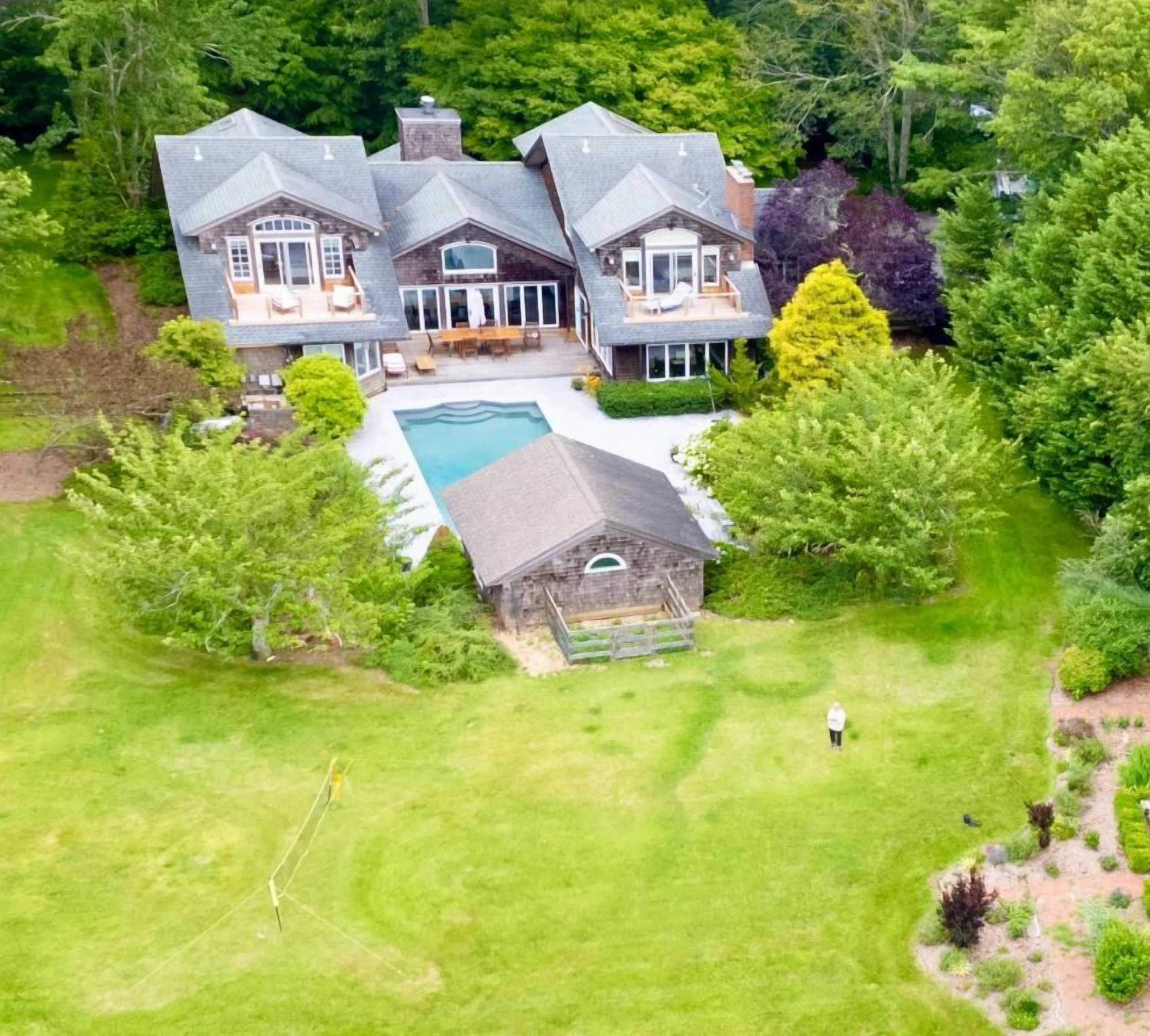 Une grande maison à plusieurs étages, dotée d’une piscine et d’une pelouse bien entretenue.