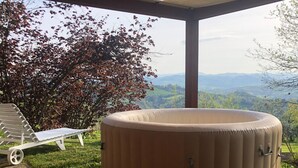 A hot tub in a covered outdoor area with a view of the mountains. - VILLA CUBETTO, an oasis of relaxation in the hills of Romagna (Emilia-Romagna)