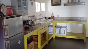 A kitchen with a stainless steel refrigerator, a yellow countertop, and a window above the sink. - VILLA CUBETTO, an oasis of relaxation in the hills of Romagna (Emilia-Romagna)