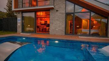A modern house with a swimming pool, large windows, and a stone facade.