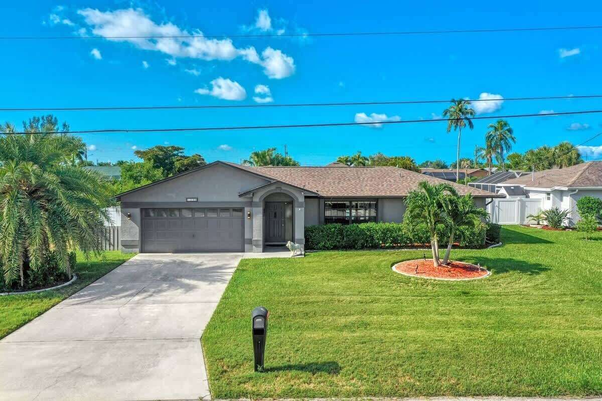 Una casa residencial con garaje, césped bien cuidado y cielo despejado.