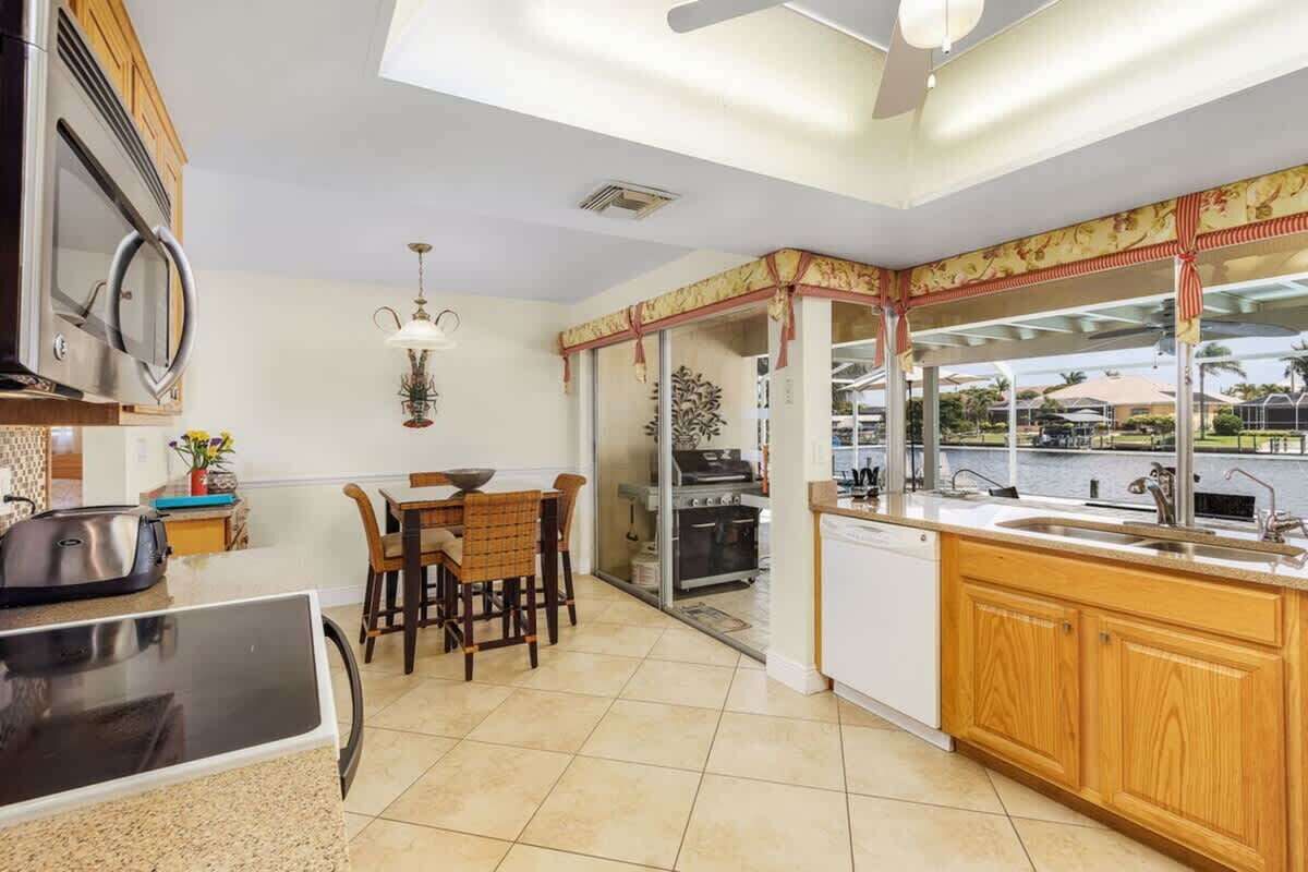 A modern kitchen with a dining area, a view of the outdoors, and a large window.