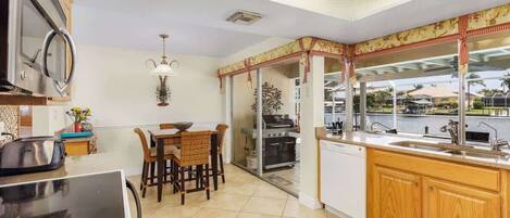 A modern kitchen with a dining area, a view of the outdoors, and a large window.
