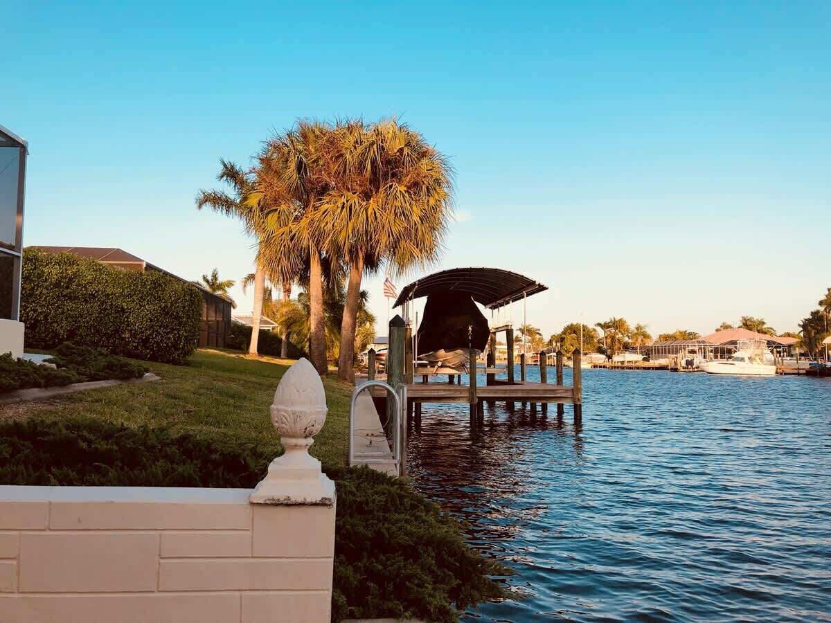 A waterfront property with a dock, a gazebo, and a palm tree.