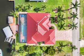 An aerial view of a property with a red-roofed building, a swimming pool, and a dock. - Vacation Villa Coral Laguna (Cape Coral)