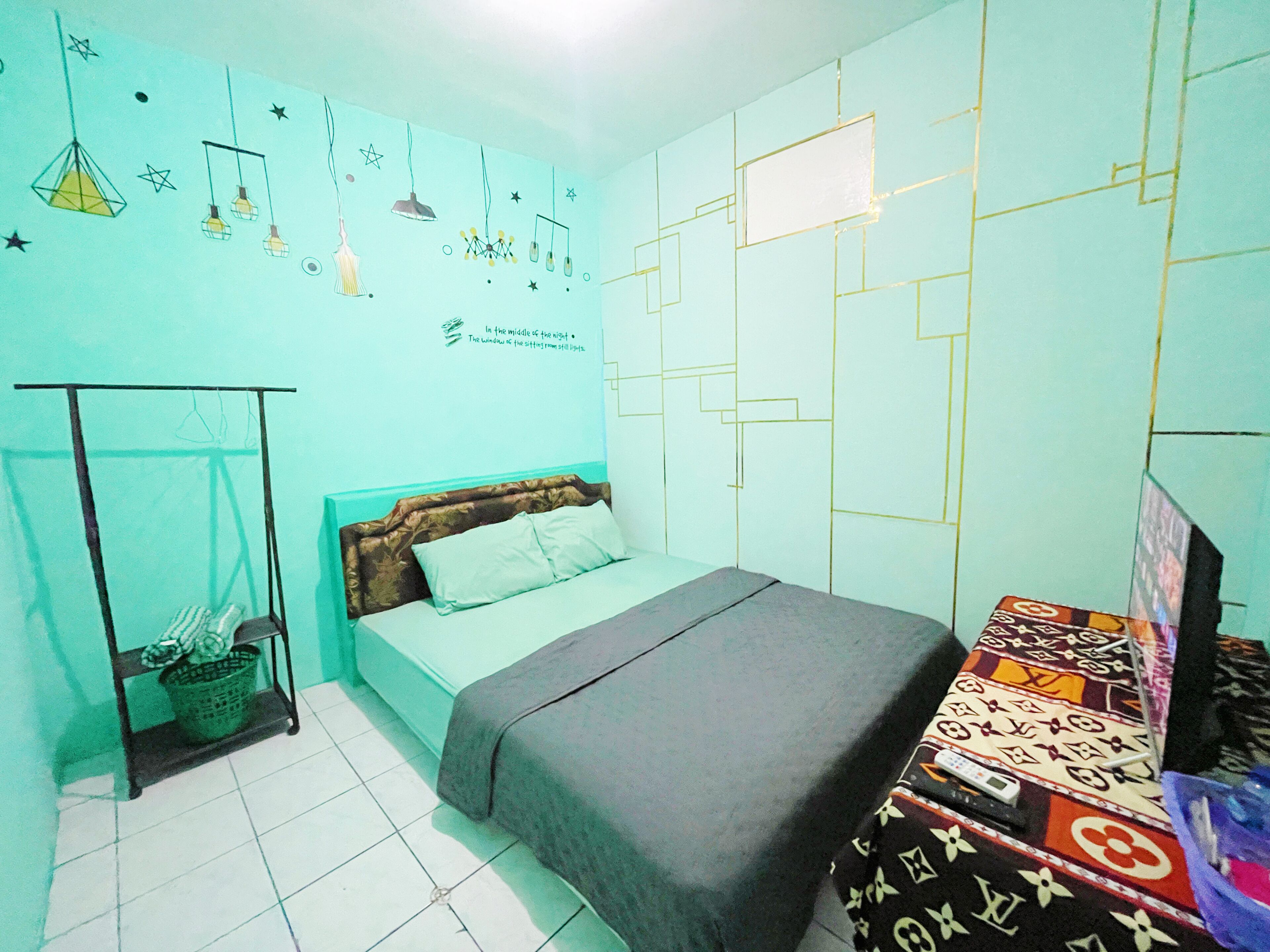 Un dormitorio con cama, mesita de noche, lámpara colgante y pared con patrones geométricos.