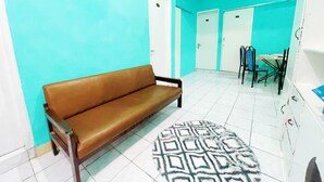 Una habitación con un sofá marrón, un tapete estampado y un comedor con sillas y una mesa.