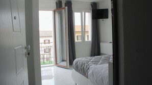 A bedroom with a bed, a TV mounted on the wall, and a sliding glass door leading to a balcony. - La rosa dei Pepoli (Castiglione dei Pepoli)