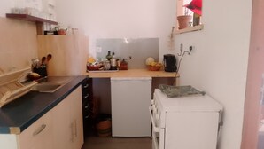 A compact kitchen with a sink, a small refrigerator, and a countertop with various items.