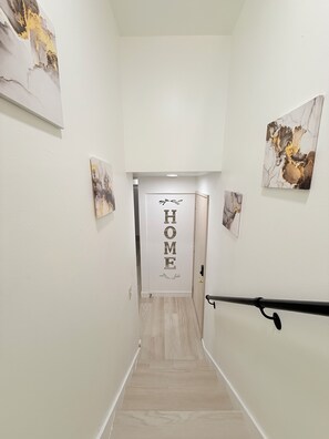 Un pasillo con un letrero que dice 'HOME', suelo de madera y obras de arte en las paredes.