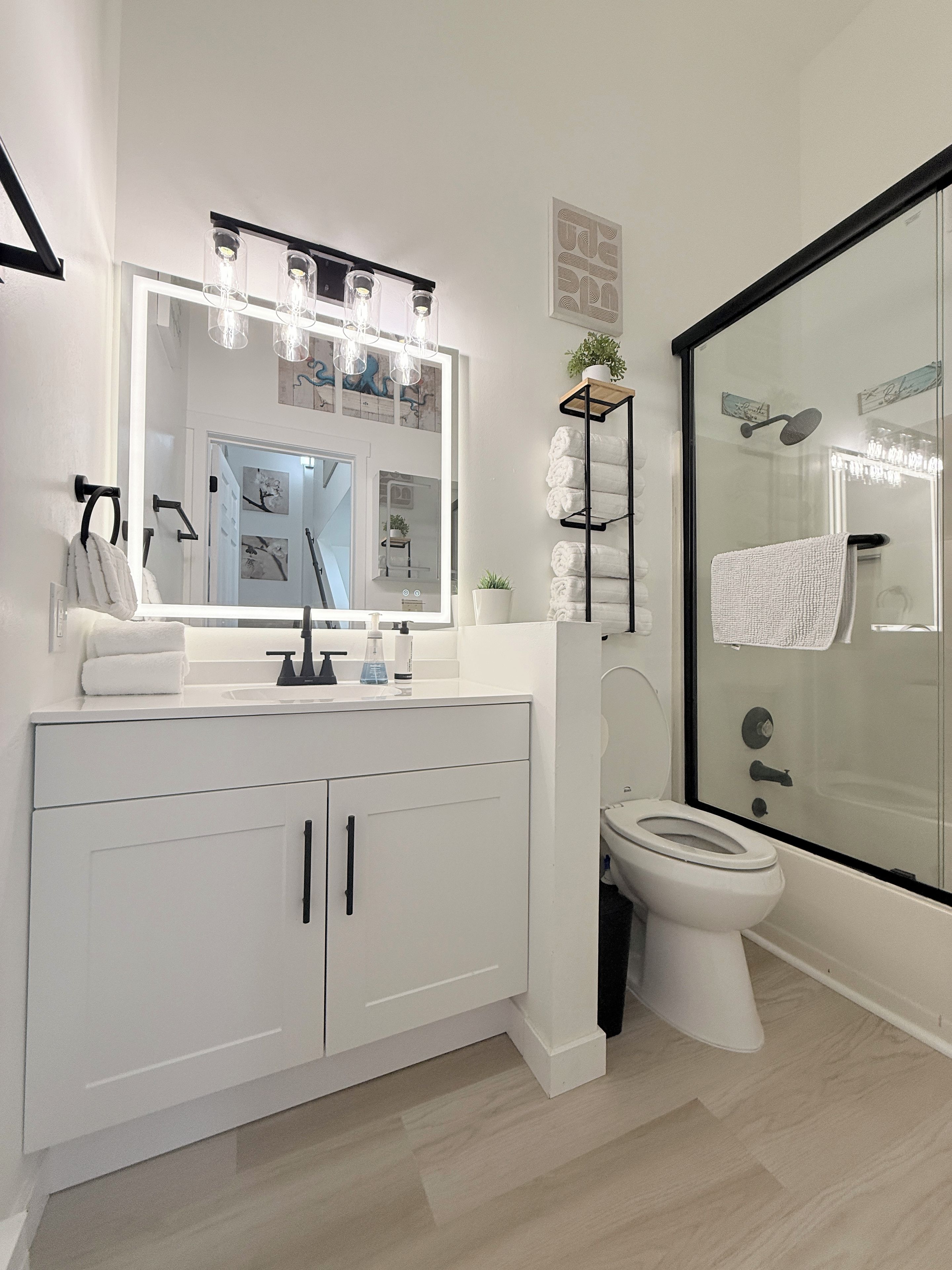 Une salle de bain moderne avec un grand miroir, une douche en verre et un meuble-lavabo blanc.