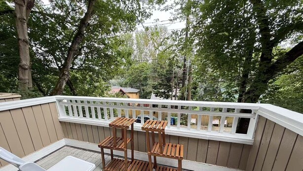 Una terraza cubierta con barandas blancas, mesas y sillas de madera.
