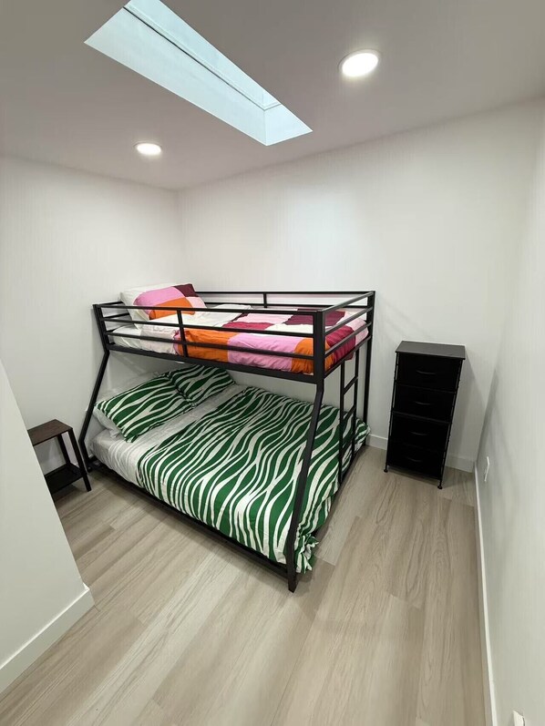 Dormitorio con literas, una pequeña mesa de estudio y un mueble de almacenamiento negro.