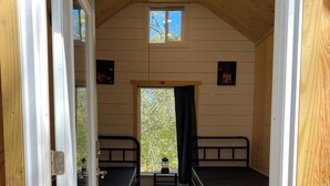 A compact room with two beds, a small table, and a window with a view of trees.