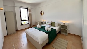 Una habitación de hotel con una cama, mesitas de noche, un espejo y una ventana con cortinas.