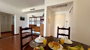 Un comedor con una mesa lista para el desayuno, que incluye platos de fruta, cruasanes y jugo.