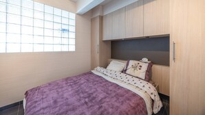 Un dormitorio con cama, ventana y armarios empotrados de madera.