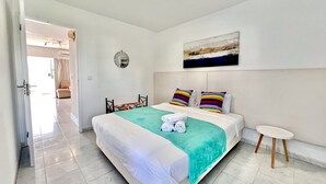 Moderni hotellihuone, jossa on suuri sänky, pieni pyöreä pöytä ja näkymä käytävälle.
